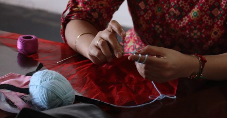 Crocheting - A woman is sewing a red and blue ball