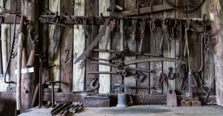 Rusty Tools - Black Metal Tools Hanged on a Rack Near Table