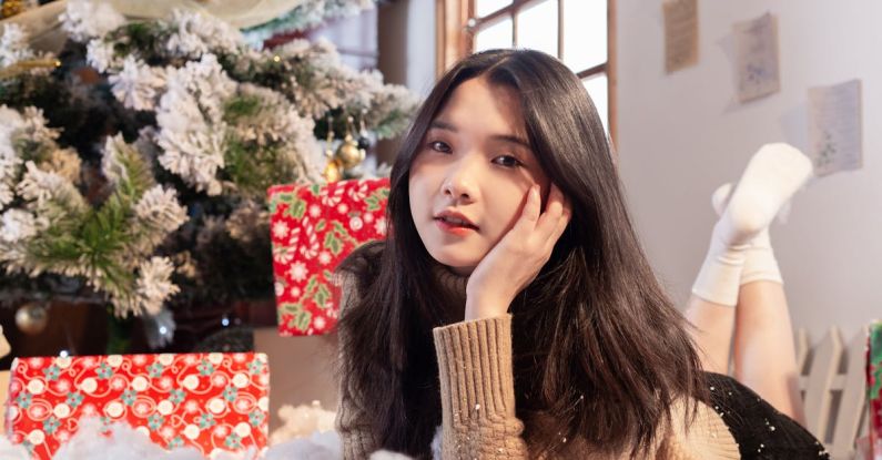 Sustainable Gifts - A woman laying on the floor next to a christmas tree