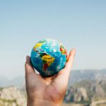 Earth Day - Person Holding World Globe Facing Mountain