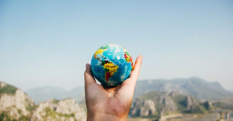 Earth Day - Person Holding World Globe Facing Mountain