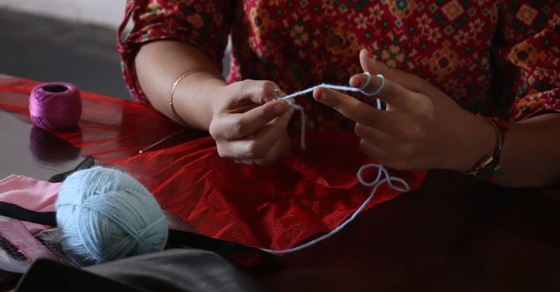 Knitting Projects - A woman is knitting a ball of yarn with a needle