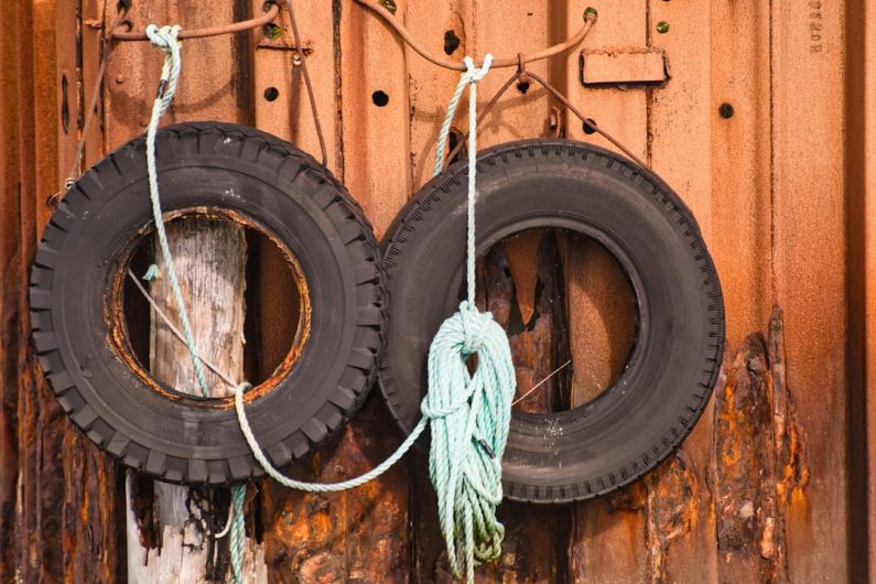 Old Tires - two old tires hanging on a rusty wall